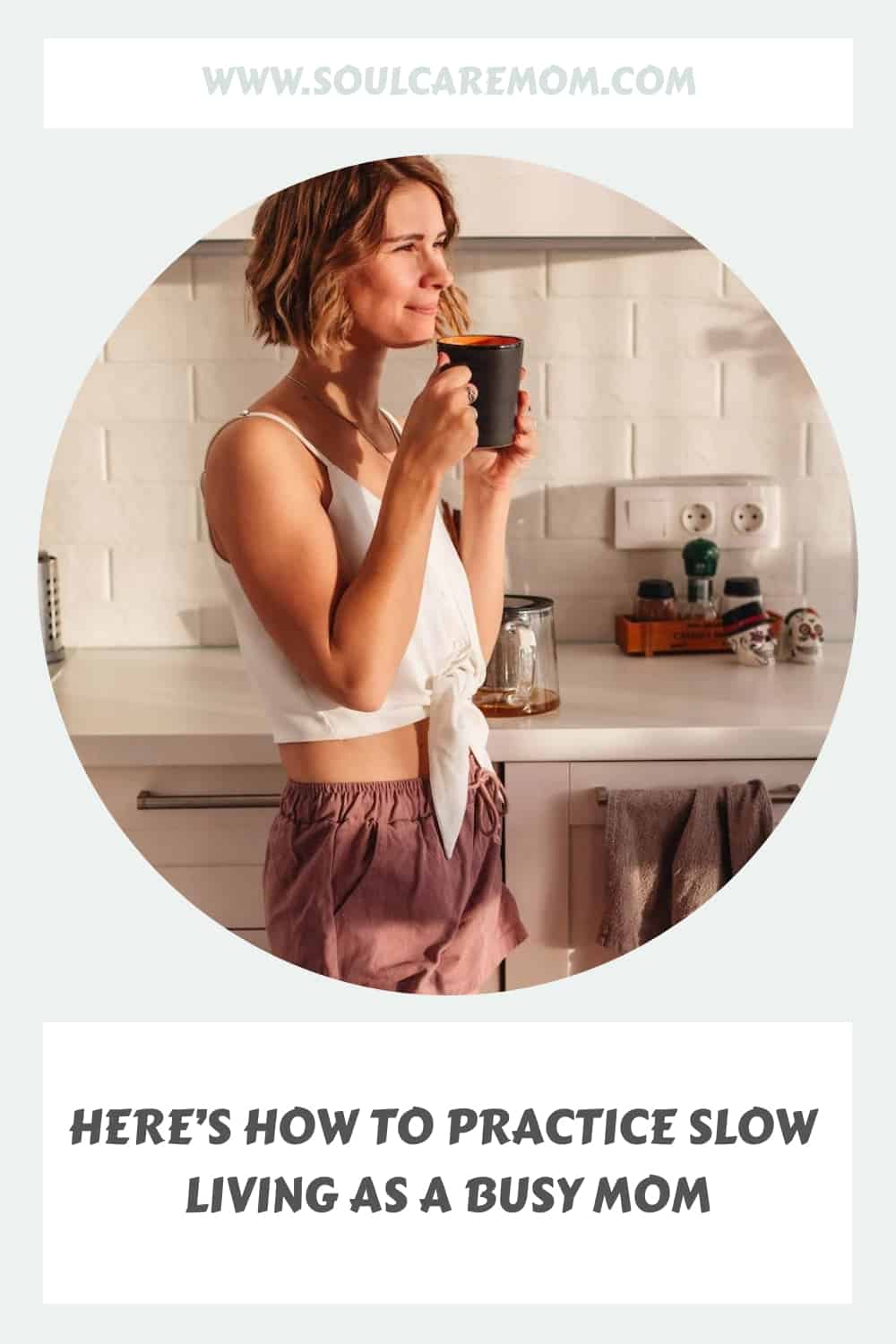 woman practicing slow living standing in a kitchen drinking a cup of tea and watching the sun rise