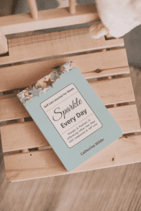 Sparkle Every Day - Self Care Journal For Moms on a wooden chair