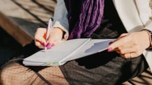 woman sitting in nature with journal prompts for mental health and emotional wellbeing