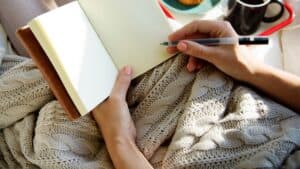 Woman sitting in bed and using Journal Prompts For Self Discovery